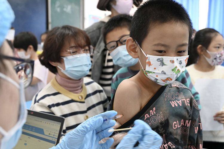 Seorang anak menerima vaksin Covid-19 di sebuah sekolah di Handan, Provinsi Hebi, China, Rabu (27/10/2021), setelah kota itu mulai memvaksinasi anak-anak berusia 3 hingga 11 tahun. Penyebaran Covid-19 di China kembali menjadi peringatan setelah klaster baru terkait sekelompok wisatawan ditemukan 17 Oktober lalu.