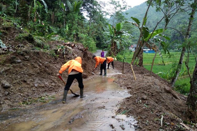 Personel Pusdalops BPBD Kabupaten Purbalingga menyingkirkan material longsor yang menutup  jalan penghubung Desa Kramat dan Sirau, Kecamatan Karangmoncol, Senin (16/10/2017).