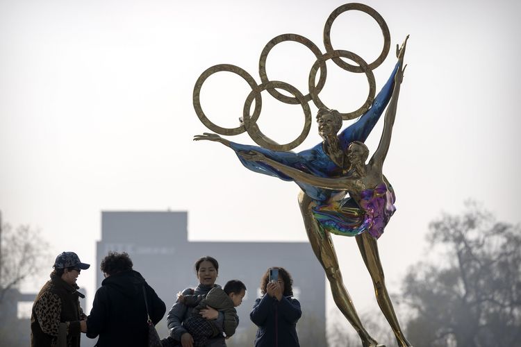 Para pengunjung berfoto di patung atlet dengan logo Olimpiade di dekat markas Komite Olimpiade Beijing (BOCOG), Kamis (18/11/2021).