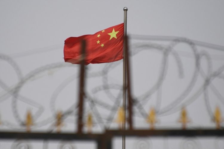 Bendera China berkibar di belakang kawat berduri di kompleks perumahan di wilayah Xinjiang barat China, 4 Juni 2019.