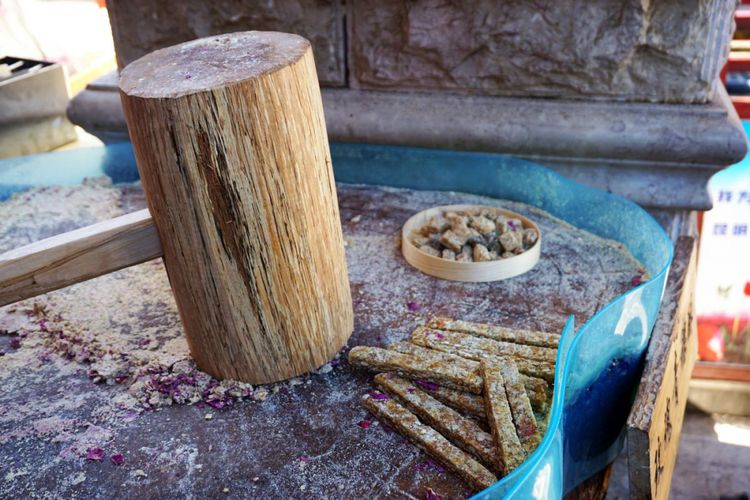 Adonan gula dan kacang dipukul di atas gelondong kayu di sebuah toko di Yunnan Ethnic Village.