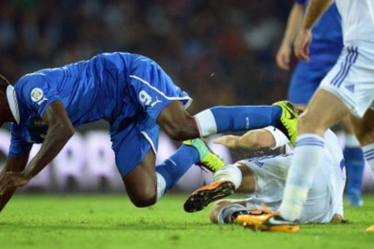 Striker tim nasional Italia, Mario Balotelli (biru), terjatuh setelah menerima tekel dari salah satu pemain Armenia pada laga kualifikasi Piala Dunia 2014 Grup B Zona Eropa, di Stadion San Paolo, Naples, Selasa (15/10/2013). Italia bermain imbang 2-2 melawan Armenia.