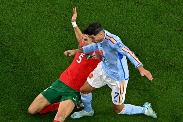 Penyerang timnas Spanyol, Alvaro Morata (kanan), diadang oleh pemain belakang timnas Maroko, Nayef Aguerd, dalam laga babak 16 besar Piala Dunia 2022 Qatar yang digelar di Stadion Education City, Al Rayyan, pada Selasa (6/12/2022). (Photo by MANAN VATSYAYANA / AFP)