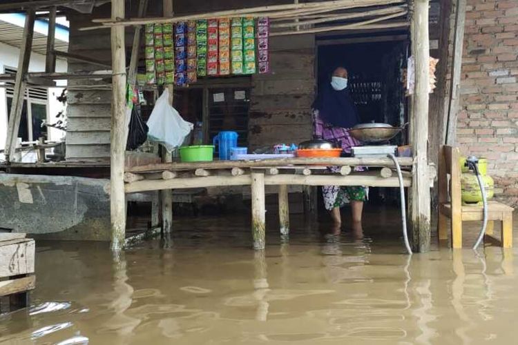 Rita (50), seorang warga Kelurahan Bambu Kuning, Kecamatan Tenayan Raya, Kota Pekanbaru, Riau, tetap berjualan meski dilanda banjir, Selasa (25/10/2021).