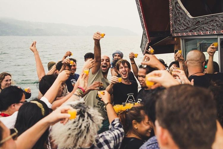 Peserta boat party di event yang digelar Volcano Floating Party menunjukkan minumannya di atas kapal di Danau Toba. 