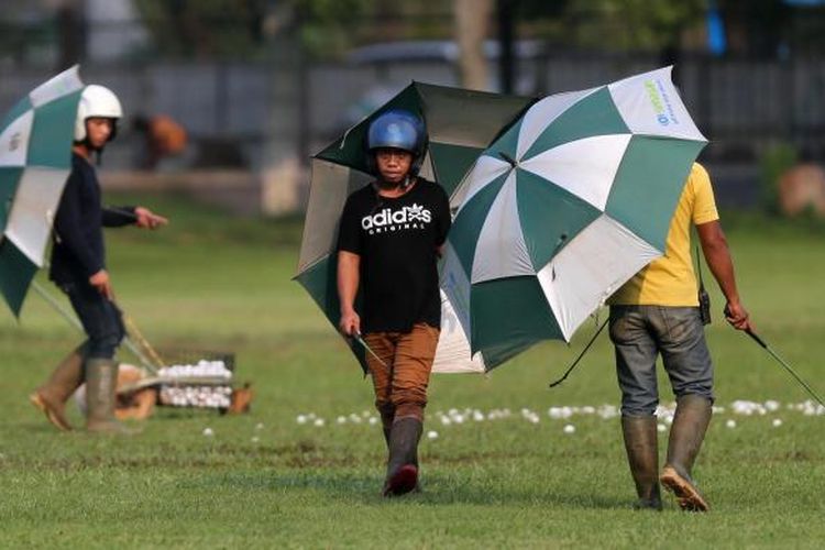 Beberapa pekerja mengumpulkan bola golf di Senayan Golf Driving Range, Jakarta, Rabu (16/7/2014). Demi keselamatan saat bekerja, mereka menggunakan helm dan payung agar terhindar dari pukulan bola. KOMPAS/TOTOK WIJAYANTO