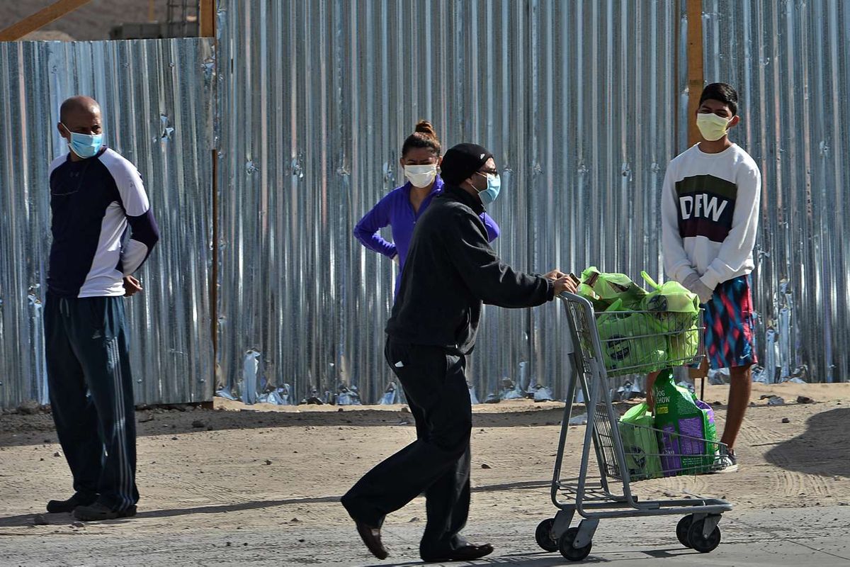 Seorang pria yang usai berbelanja melewati sejumlah warga yang mengantre dengan menjaga jarak aman saat akan berbelanja di supermarket, di Tegucigalpa, Honduras, 19 Maret 2020. Menjaga jarak aman antar warga merupakan salah satu cara yang dianjurkan untuk mencegah penyebaran virus corona.