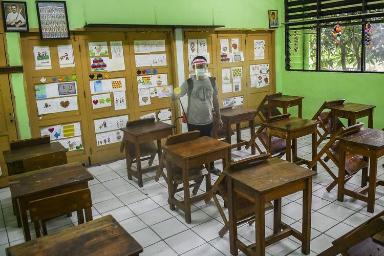 Petugas menyemprotkan disinfektan di ruang kelas SD Kenari 08 Pagi, Jakarta, Jumat (18/6/2021). Pemerintah Provinsi DKI Jakarta memutuskan untuk menghentikan sementara proses uji coba sekolah tatap muka karena lonjakan kasus COVID-19 dalam sepekan terakhir pascalibur lebaran. ANTARA FOTO/Galih Pradipta/aww.