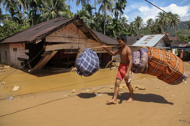 Warga memanggul barang-barang miliknya saat melintas di area banjir bandang dan longsor di Kelurahan Huta Nabolon, Kecamatan Tukka, Kabupaten Tapanuli Tengah, Sumatera Utara, Rabu (3/12/2025). Berdasarkan data dari BNPB hingga Rabu (3/12)) jumlah korban meninggal akibat  bencana banjir bandang dan longsor di Provinsi Aceh, Sumatera Utara, dan Sumatera Barat sebanyak 807 jiwa, 647 jiwa orang hilang dan korban luka sebanyak 2.600 jiwa. 