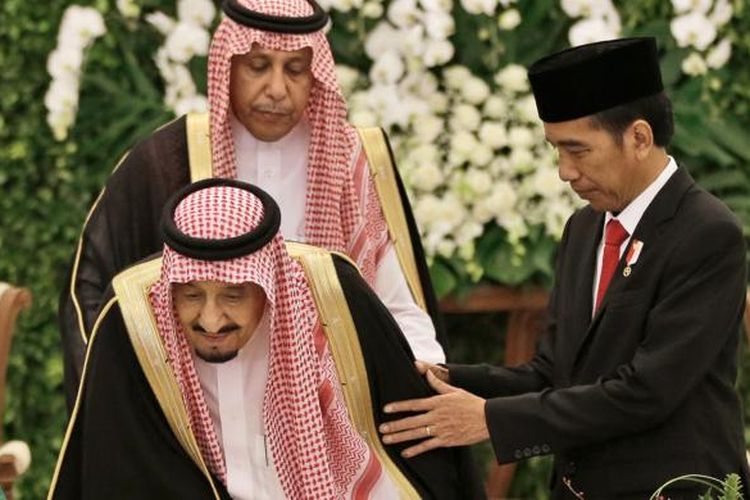 Presiden Indonesia Joko Widodo (kanan) memegang Raja Arab Saudi Salman bin Abdulaziz al-Saud saat akan duduk untuk mengisi buku tamu di Istana Kepresidenan Bogor, Jawa Barat, Rabu (1/3/2017).