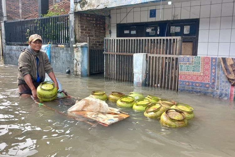 Warga di Kampung Bojongasih, Desa Dayeuhkolot, Kabupaten Bandung, Jawa Barat, beraktifitas mengangkuta gas di yengah banjir luapan sungai Citarum yang belum surut, Senin (31/11/2025)