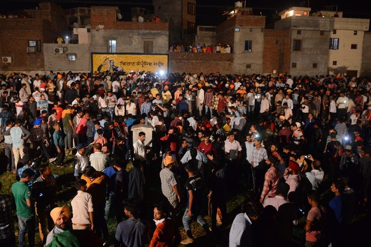 Warga berkumpul di sekitar lokasi insiden kereta api yang menabrak kerumunan pengunjung festival Dussehra di Kota Amritsar, India, pada Jumat (19/10/2018).