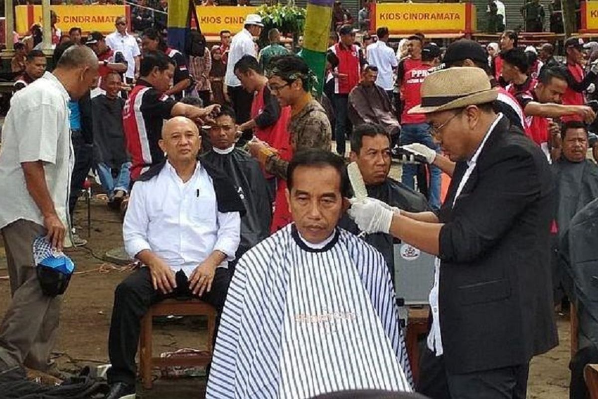 Presiden Joko Widodo dipangkas rambutnya oleh Herman, tukang cukur langganannya di acara cukur massal yang diadakan di Situ Bagendit, Kecamatan Banyuresmi, Kabupaten Garut, Jawa Barat, Sabtu (19/1/2019). 