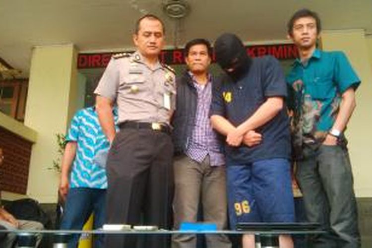 Tersangka Rudi Setiawan (35) (tengah memakai topeng hitam) yang merupakan agen judi bola di Bandung yang dibekuk Polda Jabar.