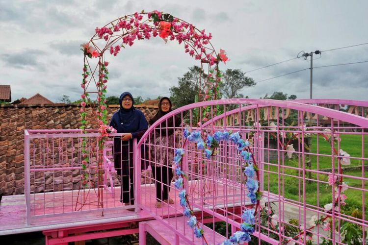 Dua pengunjung saat menikmati suasana diatasi jembatan cinta pink di spot selfie Omahe Bianca di Sleman, DI Yogyakarta, Sabtu (13/1/2018).