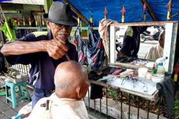 Mbah Nartowiono tukang cukur yang pinggir alun-alun Utara Yogyakarta saat melayani pelanggannya.