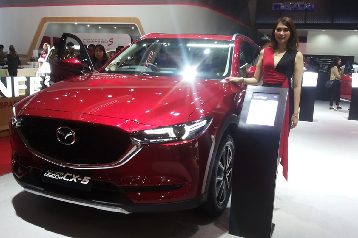 Seorang sales promotion gilr (SPG) memperkenalkan salah satu produk andalan Mazda di stan Eurokars Motor Indonesia saat hari pertama ajang Indonesia International Motor Show (IIMS) 2018 di JIExpo Kemayoran, Jakarta, Kamis (19/4/2018).