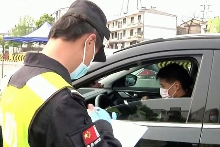 Polisi China mengawasi warga yang keluar masuk saat aturan karantina diterapkan.