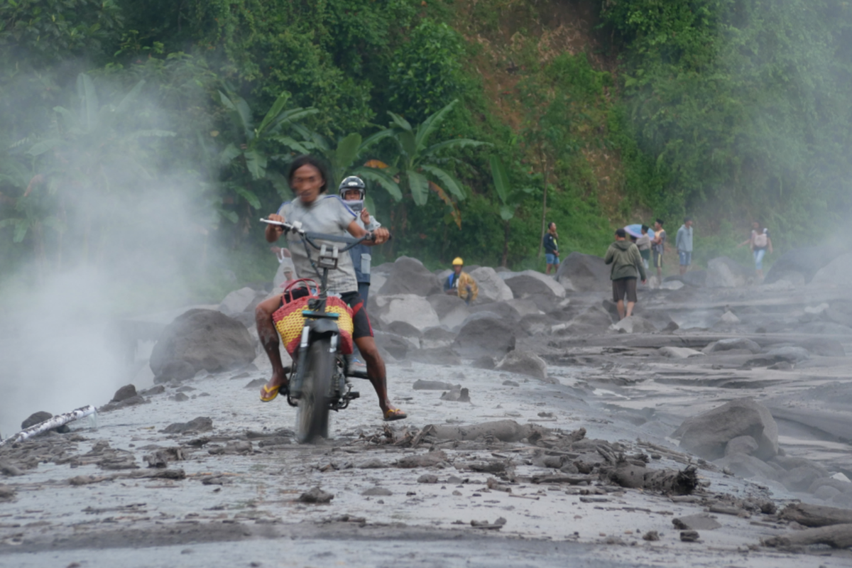 Warga nekat menyebrang di jembatan limpas Jugosari meski telah ditutupi material Semeru, Selasa (6/12/2022)