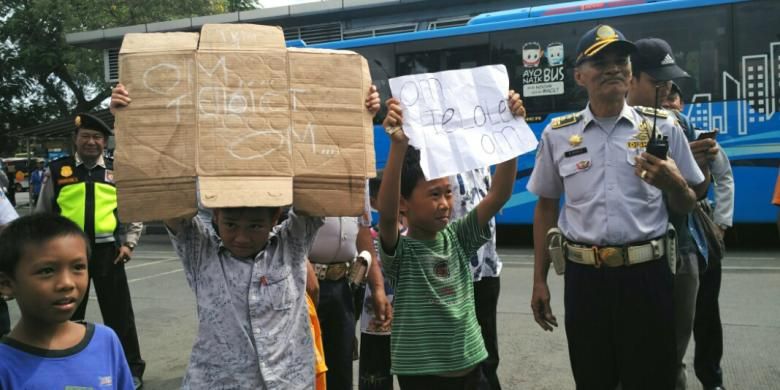 Anak-anak menunjukkan kertas dan kardus bertuliskan om telolet om kepada pengemudi bus di Terminal Kalideres, Jakarta Barat, Jumat (23/12/2016).