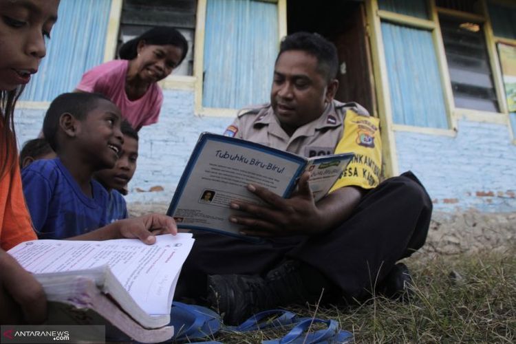 Polisi Bhabinkamtibmas Aipda Abraham Doeka (kanan) mengajari anak-anak yang putus sekolah untuk belajar membaca di desa Kabulak, Kecamatan Kakuluk Mesak, Kabupaten Belu, NTT Selasa (9/7/2019)