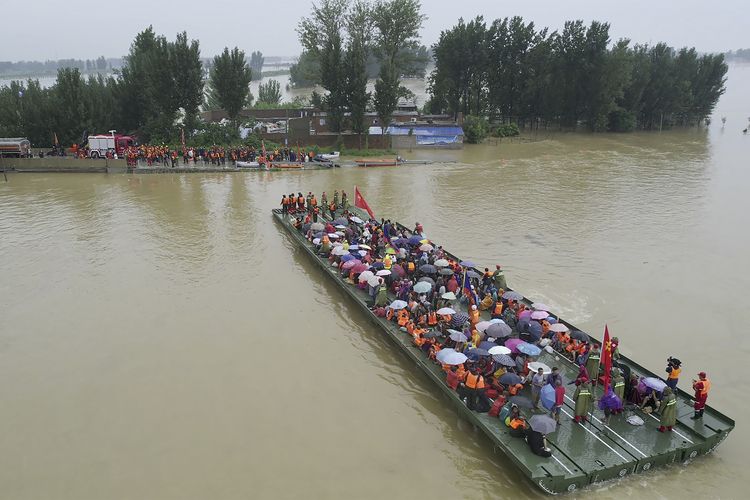 Tim penyelamat menggunakan jembatan rakit bermotor untuk mengevakuasi warga terdampak banjir China di Xinxiang, provinsi Henan, Jumat (23/7/2021). Jumlah korban tewas akibat banjir parah ini terus meningkat di kota Zhengzhou, menurut laporan media pemerintah.