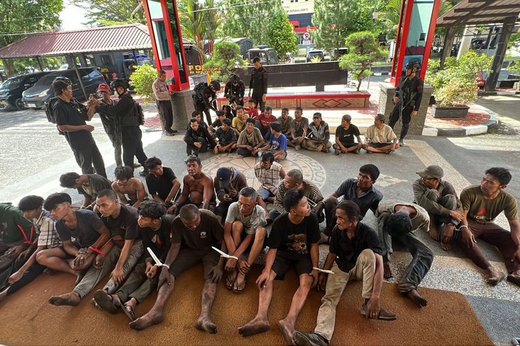 Polisi saat menangkap warga yang terlibat penjarahan besi pabrik PT ARB di Jalan Yos Sudarso, Kota Medan, Minggu (20/7/2025)