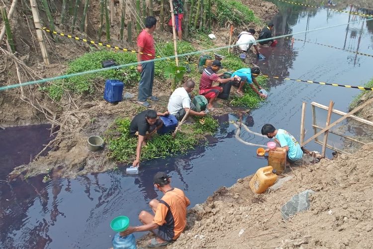 Warga menampung BBM di sungai akibat kebocoran pipa BBM Pertamina di Desa Jeruklegi Kulon, Kecamatan Jeruklegi, Kabupaten Cilacap, Jawa Tengah, Rabu (3/8/2022).