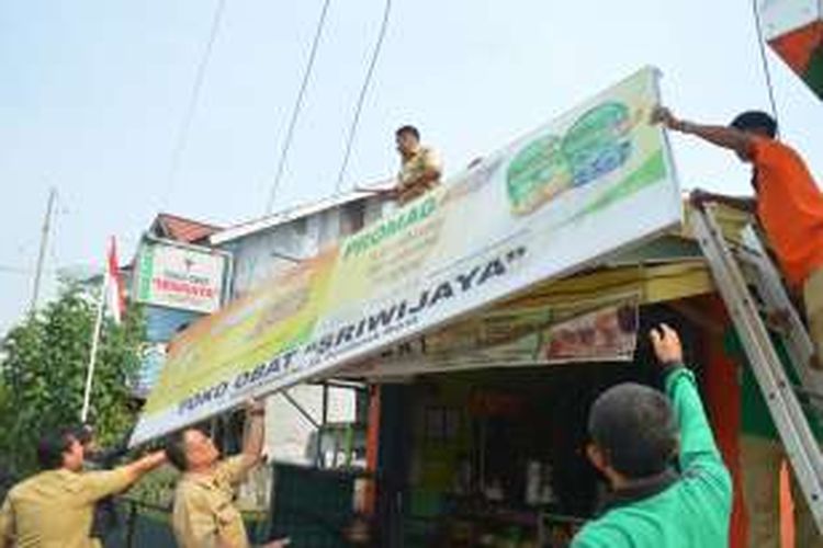 Petugas dari Dinas Pendapatan Daerah Kota Pontianak menurunkan salah satu papan reklame yang ditenggarai enggan membayar pajak di salah satu pertokoan di Pontianak (22/8/2016)