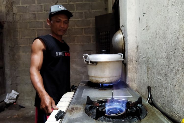 Teguh Pratikno menghidupkan kompor biogas di rumahnya di Dusun Dungus, Desa Mundu, Kecamatan Tulung, Kabupaten Klaten, Selasa (12/10/2021). Berdasarkan Biogas User Survey 2020, penghematan energi untuk memasak bisa mencapai Rp 50.000.