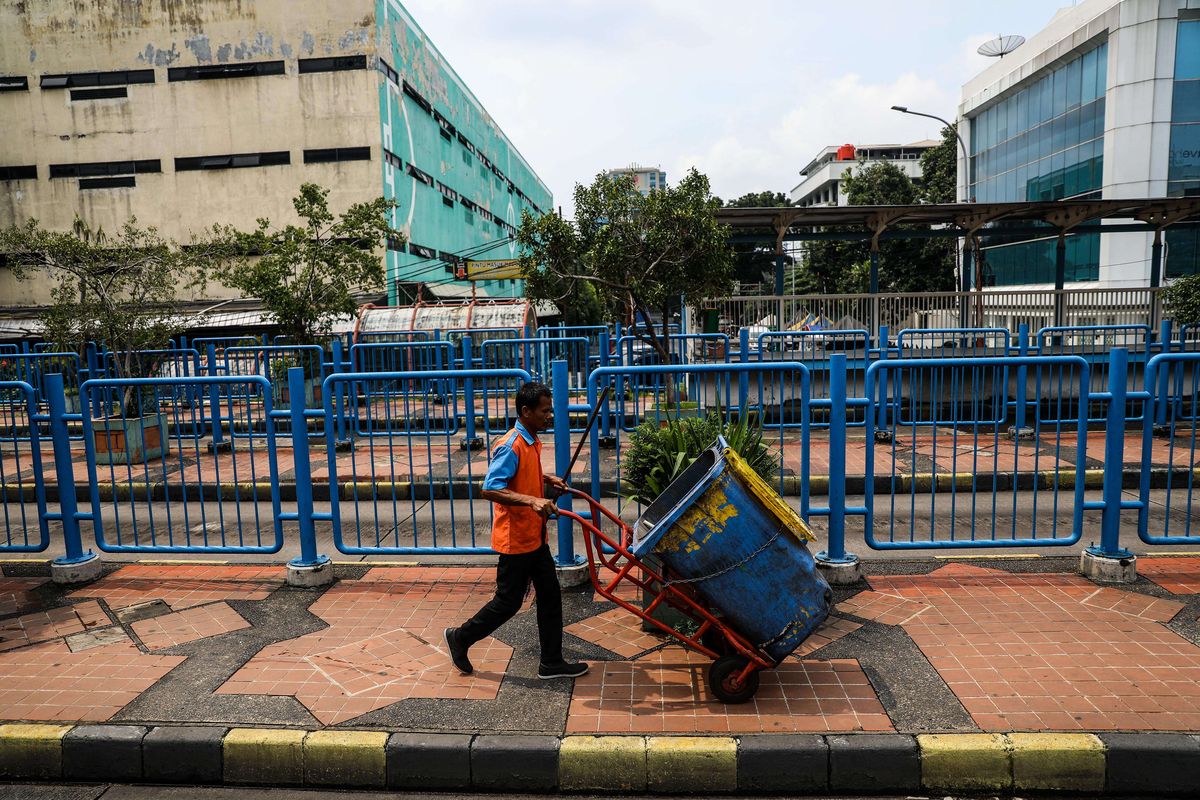 Warga melintas di jalur bus dan transjakarta yang lengang di Terminal Blok M, Jakarta Selatan, Selasa (24/3/2020). Terminal Blok M lebih lengang dibandingkan hari biasa karena sebagian perusahaan telah menerapkan bekerja dari rumah guna menekan penyebaran virus corona atau COVID-19.