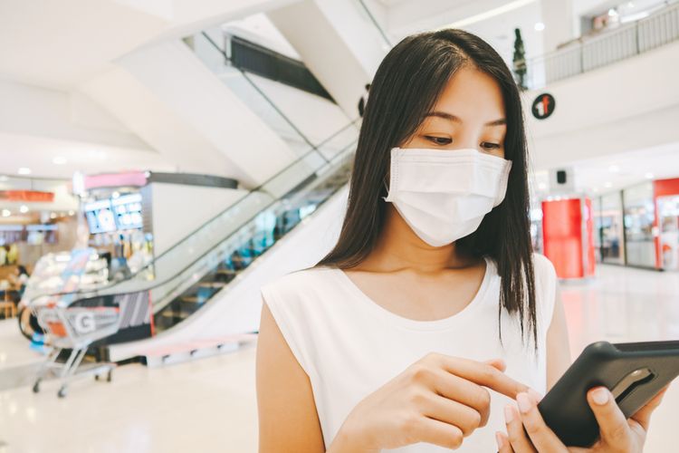 Ilustrasi seorang perempuan mengenakan masker ketika bepergian ke mall.