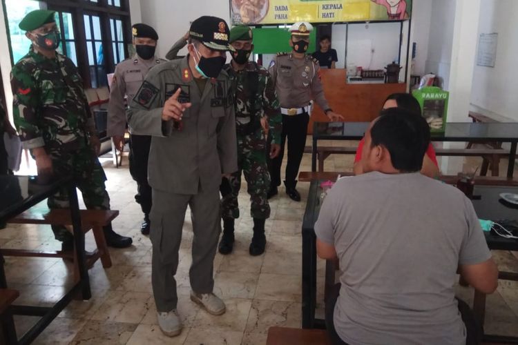 TEGUR—Kasat Pol PP Kabupaten Wonogiri, Waluyo bersama tim gabungan TNI/Polri menegur pengunjung yang nekat makan ditempat di salaj satu warung makan di Kota Wonogiri. Tak hanya pengunjung, tim gabungan juga menertibkan 46 warung makan di Kota Wonogiri karena nekat melayani makan ditempat di masa PPKM darurat.