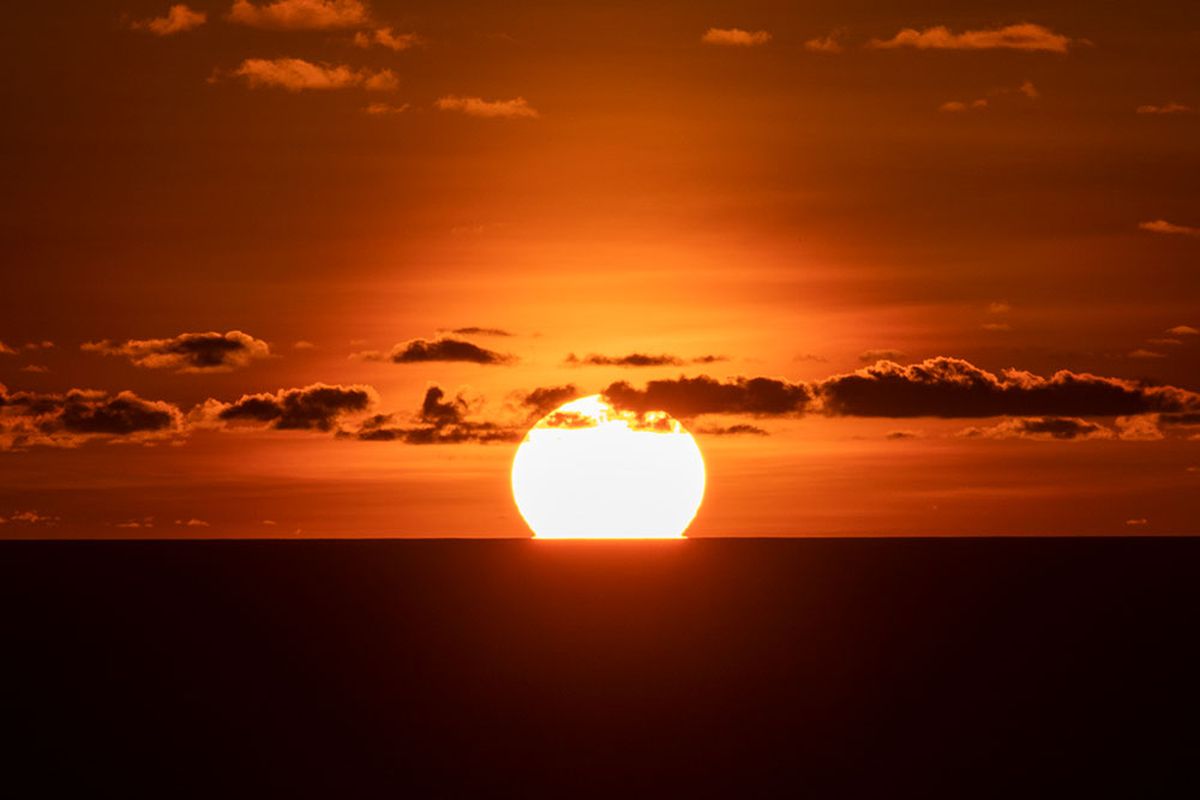 Matahari terbenam sempurna di atas lautan dilihat dari Bukit Paralayang Watugupit, Minggu (19/1/2020).