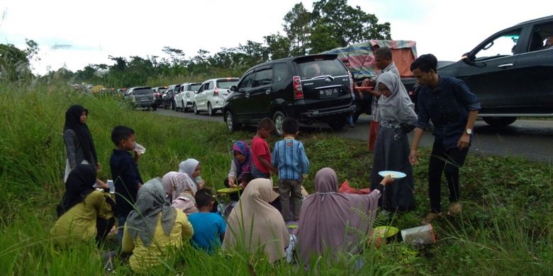 Warga bersantap sambil menunggu macet yang terurai di jalur wisata Gunung Salak, Kabupaten Aceh Utara, Aceh, Minggu (3/9/2017).