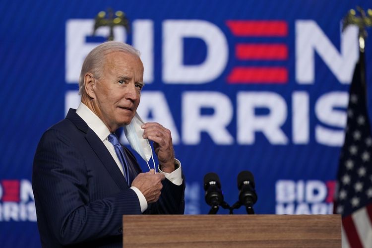 Joe Biden melepas maskernya saat hendak berpidato di Wilmington, Delaware, pada 6 November 2020.