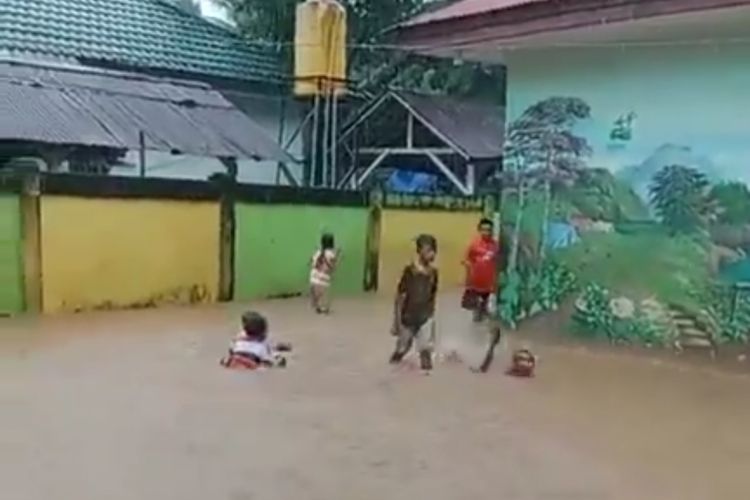 Siswa SD Negeri 39 dan SD 24 Ambon bermain di halaman sekolah mereka yang terendam banjir , Rabu (5/6/2024)