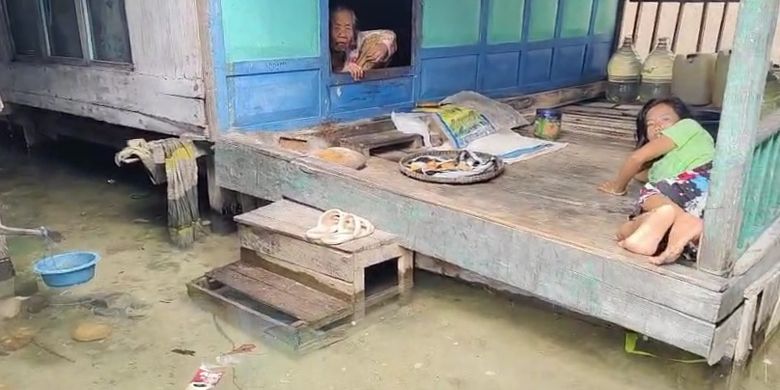 Dua orang warga di desa Saobi yang beetahan di rumah akibat banjir rob. 