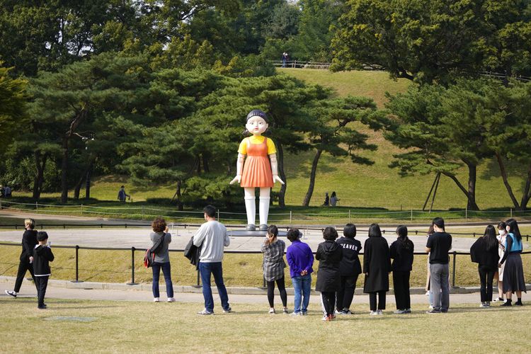 Pengunjung melihat boneka Younghee tiruan dalam serial Netflix Squid Game yang ditampilkan di taman di Seoul, Korea Selatan, Selasa (26/10/2021).