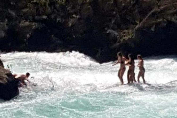 Rachael De Jong dan ketiga temannya saat berusaha melompat dari sebuah batu kecil di tengah Sungai Waikato yang ketinggian airnya bertambah setelah pintu air sebuah bendungan dibuka.