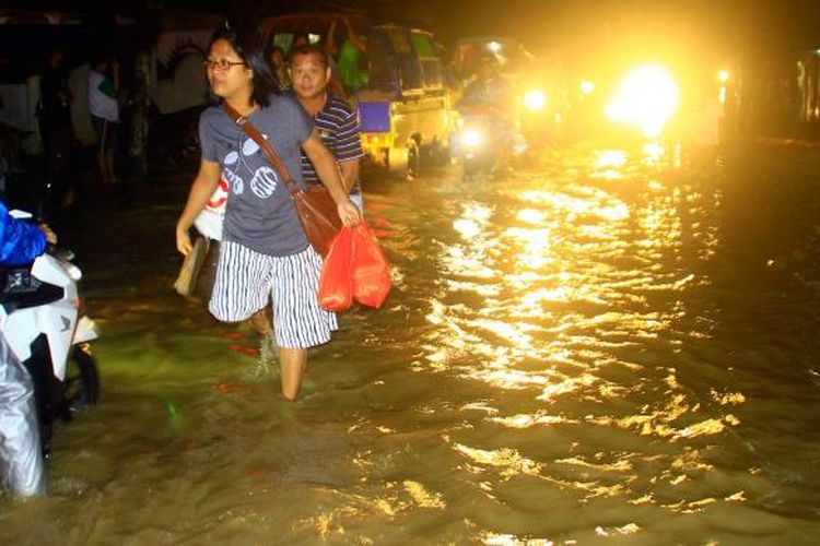Sejumlah warga mencoba menghindari air sungai yang meluap di Kelurahan Bailang, Kecamatan Bunaken, Manado, Minggu (19/2/2017) malam.
