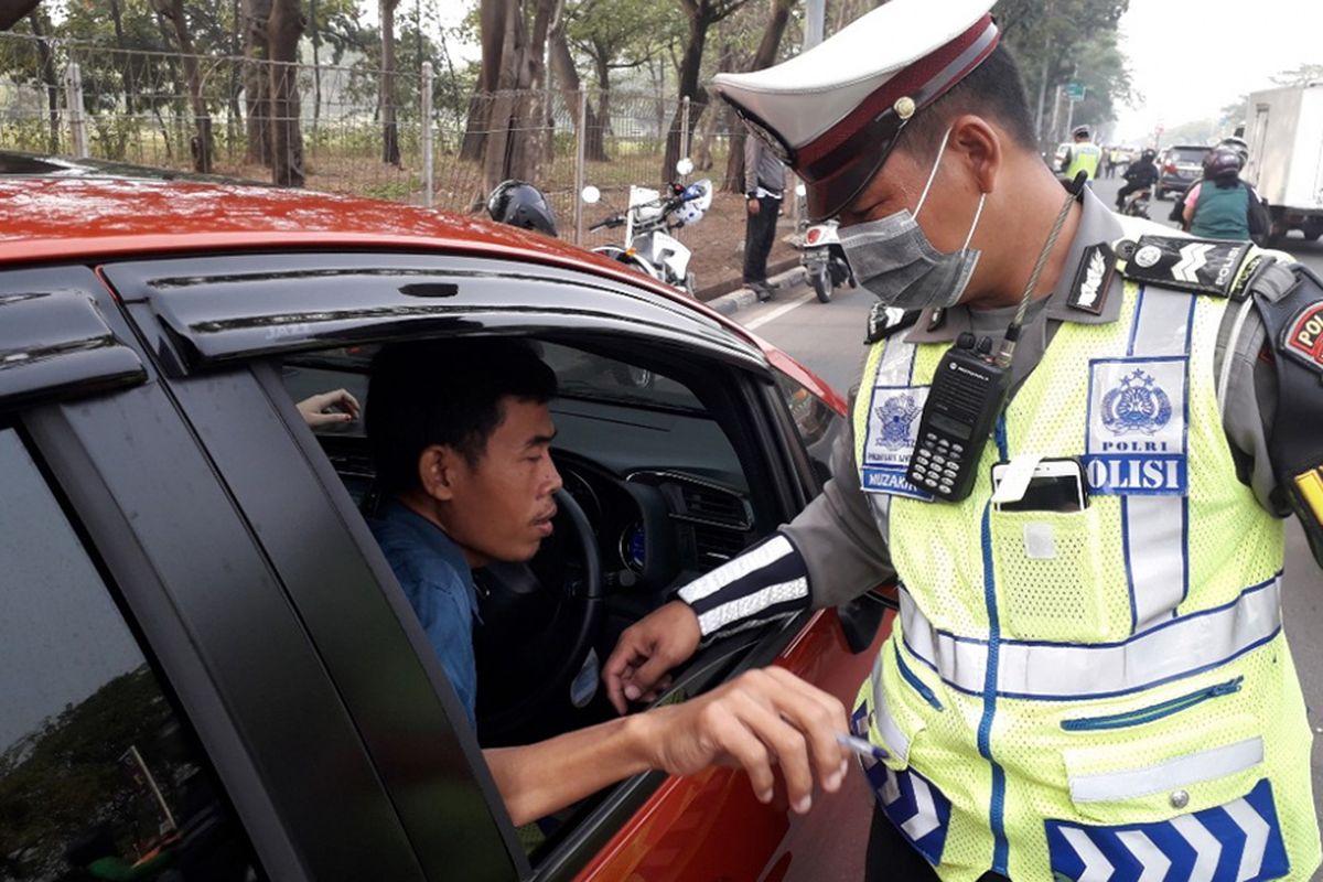 Carito, seorang pengendara, saat ditilang polisi di Jalan Benyamin Sueb, Jakarta Utara, karena melanggar aturan ganjil-genap, Rabu (1/8/2018). Petugas kepolisian mulai memberlakukan penindakan berupa tilang terhadap pengendara mobil yang melanggar di kawasan perluasan sistem ganjil-genap.