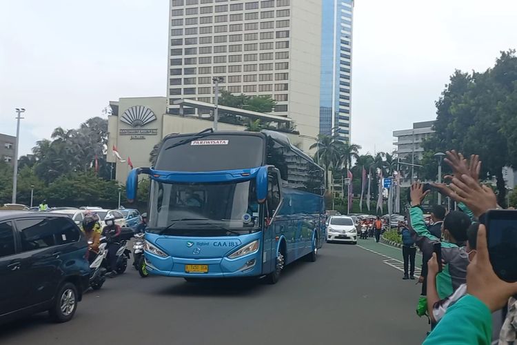 Sejumlah warga melambaikan tangan ke arah bus pariwisata yang mengangkut pebalap MotoGP menuju Bandara Soekarno Hatta, Rabu (16/3/2022).