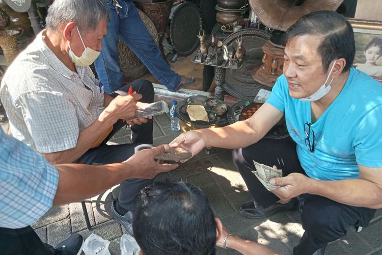 Potret wisman asal Taiwan sedang ditawari koin kuno oleh beberapa pedagang di Jalan Surabaya.