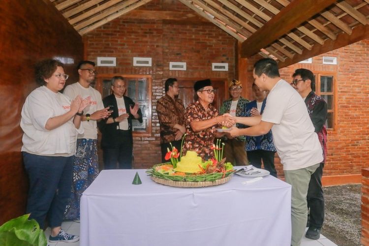 Komisaris Utama InJourney Destination Management (IDM) Muhammad Tri Andhika (kanan) menyerahkan potongan tumpeng kepada Siswanto saat peresmian rumah layak huni di kawasan Borobudur, Magelang, Kamis (15/1/2026). Inisiatif ini merupakan wujud nyata kepedulian perusahaan dalam meningkatkan kualitas hidup masyarakat di sekitar destinasi wisata. 