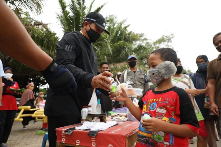 BERIKAN SUSU—Walikota Madiun, Maidi memberikan susu gratis bagi anak-anak yang berolahraga di Lapangan Gulun Kota Madiun, Minggu (4/10/2020).