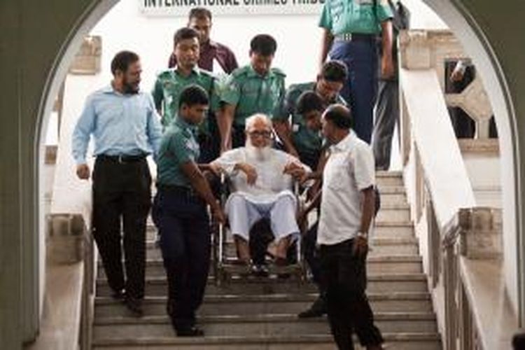 Ghulam Azam (di kursi roda), dibawa petugas meninggalkan ruang sidang di Dhaka, Banglades, Senin (15/7/2013). Pemimpin spiritual partai Jamaat-e-Islami ini dianggap bersalah mendalangi aksi kekerasan pada 1971 dan dijatuhi hukuman penjara 90 tahun.