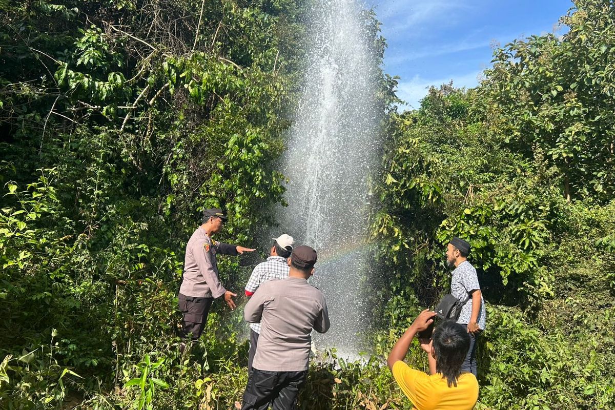 Anggota Polsek Pasongsongan dan warga saat berada di lokasi semburan air bercampur gas setinggi 20 meter di Desa Prancak, Kec. Pasongsongan, Kab. Sumenep, Jawa Timur.