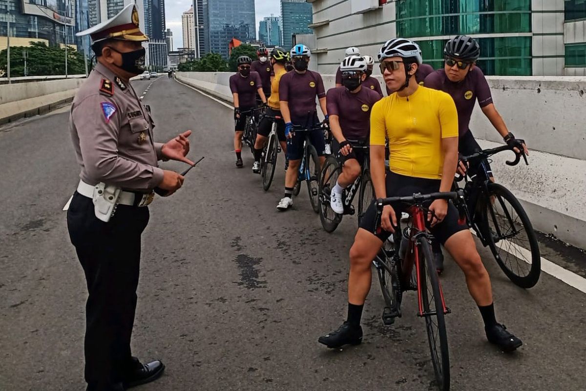 Petugas kepolisian menegur rombongan pesepeda yang nekat melintasi Jalan Layang Non Tol (JLNT) Casablanca, Jakarta, Minggu (14/11/2021).