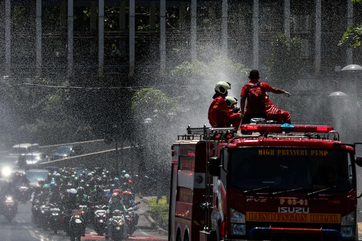 Petugas Pemadam Kebakaran (Damkar) menyemprotkan disinfektan di sepanjang jalan protokol dari monas sampai bunderan senayan di Jakarta, Selasa (31/3/2020). Penyemprotan disinfektan dalam rangka mitigasi pencegahan virus corona (COVID-19).